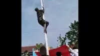 Seorang prajurit TNI memanjat tiang bendera untuk ambil tali yang tertarik ke atas