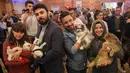 Orang-orang berpose dengan kucing mereka selama kontes kecantikan kucing internasional ke-3 di Ankara, Turki, 14 Oktober 2018. Ajang ini dijadikan para penghobi dan kolektor kucing untuk unjuk kebolehan dan unjuk kecantikan. (ADEM ALTAN/AFP)