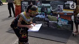 Demonstran melakukan aksi teatrikal saat unjuk rasa di kawasan Bundaran Patung Kuda Arjuna Wijaya, Jakarta, Senin (21/6/2021). Aksi yang dilakukan bertepatan dengan ulang tahun Presiden Joko Widodo ini sebagai bentuk kecaman dan penolakan terhadap revisi UU Minerba. (Liputan6.com/Angga Yuniar)