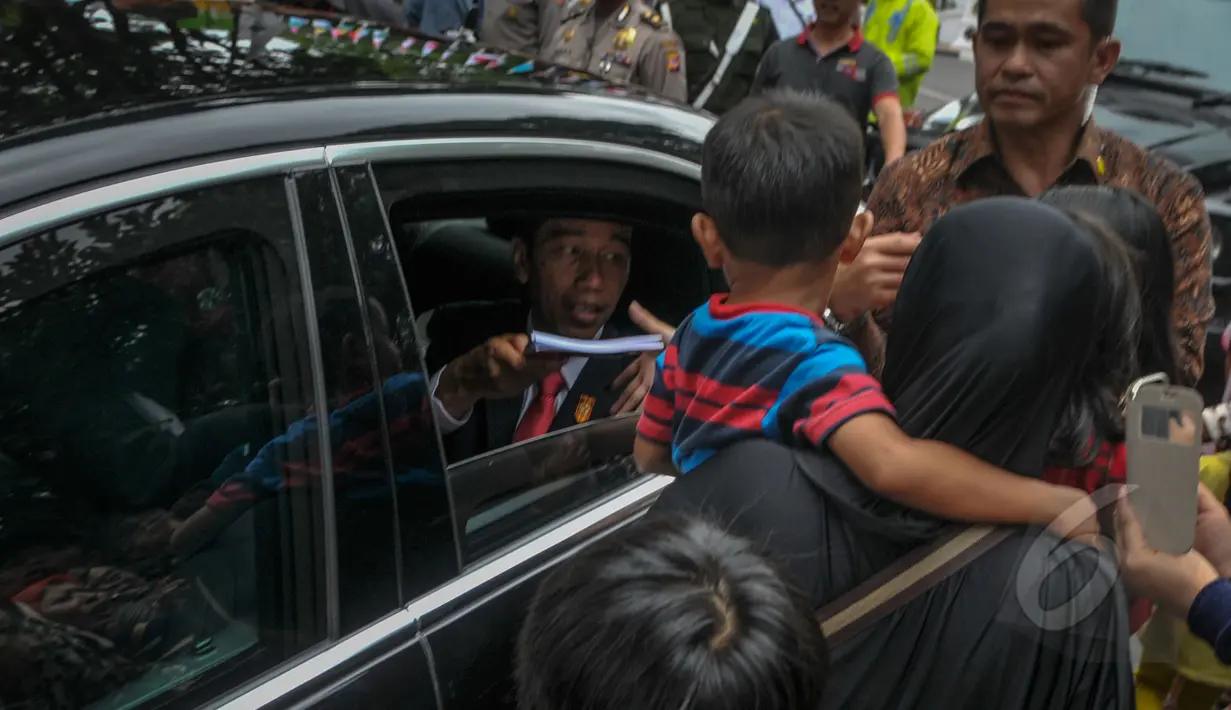 Presiden Joko Widodo membagikan buku kepada warga seusai acara makan siang bersama kepala negara serta delegasi negara-negara peserta Konferensi Asia Afrika di Jalan Cicendo, Bandung, Jumat (24/4/2015). (Liputan6.com/Faizal Fanani)