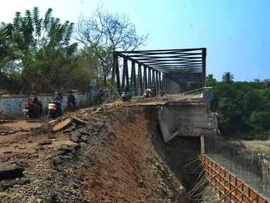 Pengendara roda dua melintasi jalan longsornya tepian jembatan Cipamingkis Cibarusah, Kab Bekasi, Jawa Barat (15/7). Sudah lebih empat bulan jembatan tersebut tertutup bagi kendaraan roda empat. (Merdeka.com/Arie Basuki)