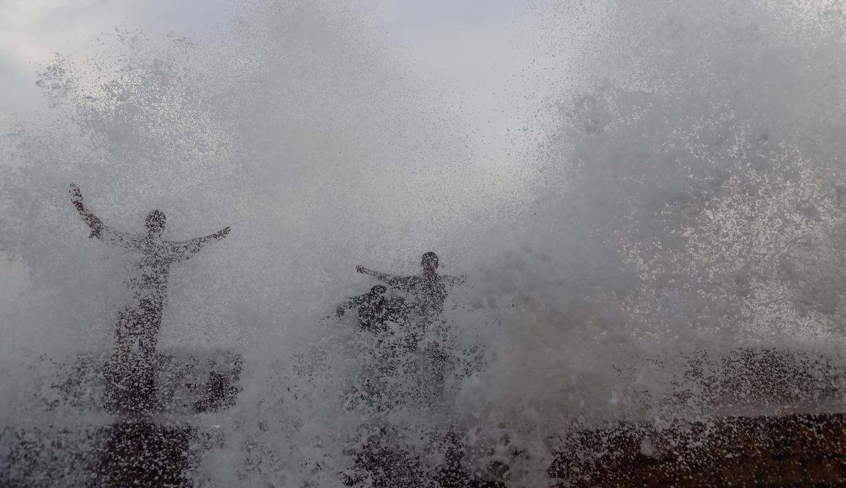 Orang-orang menikmati percikan air ombak selama musim panas di laut Arab di Karachi (14/6/2019). Memasuki musim panas, warga Pakistan ramai-ramai mendinginkan tubuhnya di laut. (AFP Photo/Asif Hassan)
