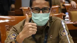 Menteri Pariwisata dan Ekonomi Kreatif Sandiaga Uno mengenakan masker saat Rapat Kerja dengan Komisi X di gedung DPR RI, Jakarta, Kamis (14/1/2021). Sandiaga Uno tampil dengan kemeja coklat dan celana hitam saat mengikuti rapat tersebut. (Liputan6.com/Angga Yuniar)