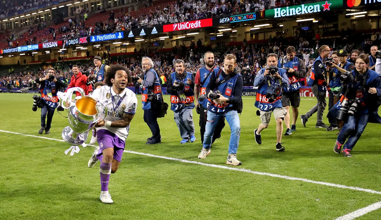 Pemain Real Madrid Marcelo membawa piala saat merayakan kemenangannya usai melawan Juventus dalam final Liga Champions di Stadion Cardiff, Wales (3/6). (Nick Potts/PA via AP)