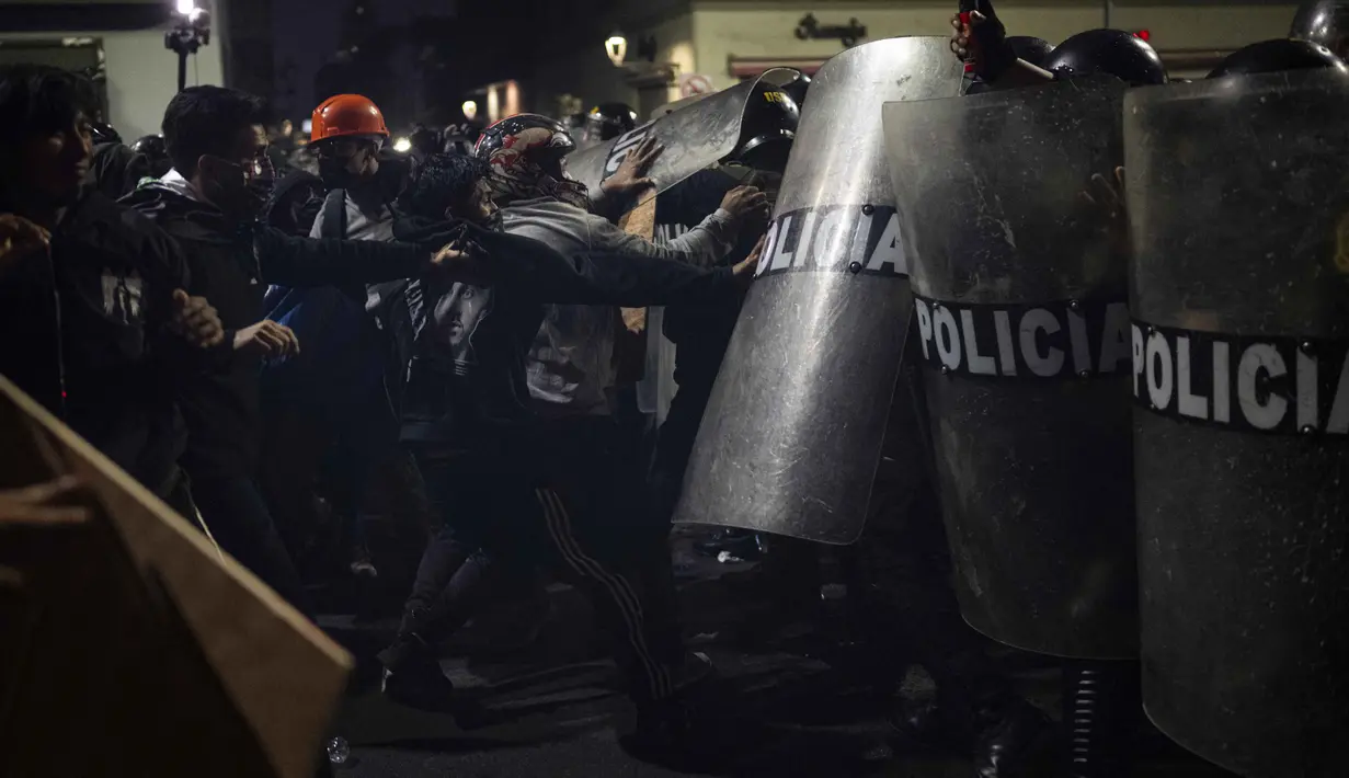 Sejumlah orang mencoba mendobrak barisan personel keamanan saat aksi unjuk rasa yang berlangsung di pusat Kota Lima, Peru pada 21 September 2025. (ERNESTO BENAVIDES/AFP)