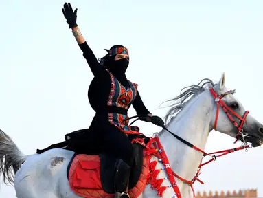 Perempuan Arab melambaikan tangan saat menunggangi kuda dalam Festival Souk Okaz 2019 di Kota Taif, Arab Saudi, Rabu (7/8/2019). Tahun ini merupakan pertama kalinya perempuan diizinkan untuk berpartisipasi dalam Festival Souq Okaz 2019. (AMER HILABI/AFP)
