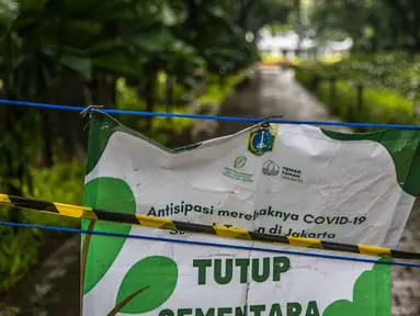 Spanduk penutupan dipasang di Taman Menteng, Jakarta, Kamis (31/12/2020). Pemprov DKI Jakarta mulai hari ini menutup sementara seluruh taman dan hutan kota di Ibu Kota jelang Tahun Baru 2021 untuk mengantisipasi penyebaran virus Covi-19. (Liputan6.com/Faizal Fanani)