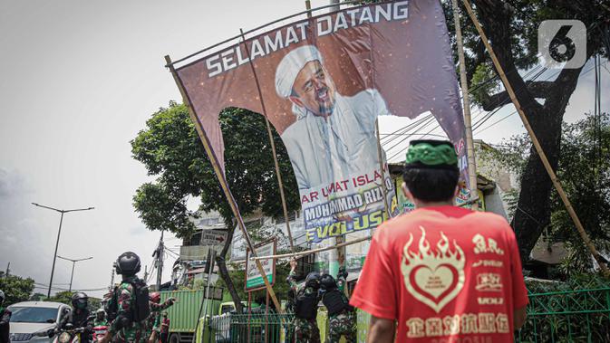 Seorang warga meminta anggota TNI untuk tidak mencopot paksa baliho Rizieq Shihab yang terpasang di sekitar kawasan Petamburan, Jakarta, Jumat (20/11/2020). Pencopotan dilakukan karena menyalahi aturan yang telah ditetapkan. (Liputan6.com/Faizal Fanani)