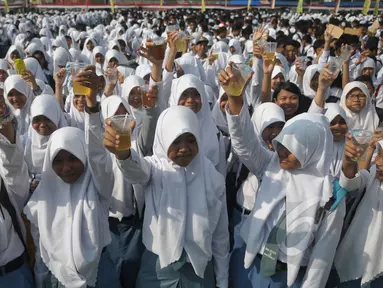 Ribuan pelajar mengangkat gelasnya saat minum jamu bersama di Alun-Alun Satya Negara Sukoharjo, Jawa Tengah, Rabu (1/4). Kegiatan tersebut dalam rangka pelestarian jamu ke masyarakat nasional maupun internasional. (Liputan6.com/Johan Tallo)