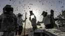 <p>Peternak lebah Palestina mengumpulkan madu dari sarang lebah di tempat pemeliharaan lebah selama musim panen tahunan di Khan Yunis di Jalur Gaza selatan pada 9 Mei 2022. Beberapa peternak juga memanfaatkan lebah untuk terapi kesehatan melalui sengatannya. (SAID KHATIB / AFP)</p>