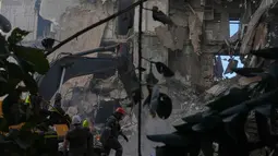 Dengan menggunakan 50 jet tempur, serangan Israel menghantam 100 target dalam waktu hanya 10 menit. Tampak dalam foto, para pekerja pertahanan sipil Lebanon dan sebuah ekskavator membersihkan puing-puing di lokasi bangunan yang hancur akibat serangan udara Israel sehari sebelumnya di pusat kota Beirut, Lebanon, Kamis 9 April 2026. (AP Photo/Hassan Ammar)