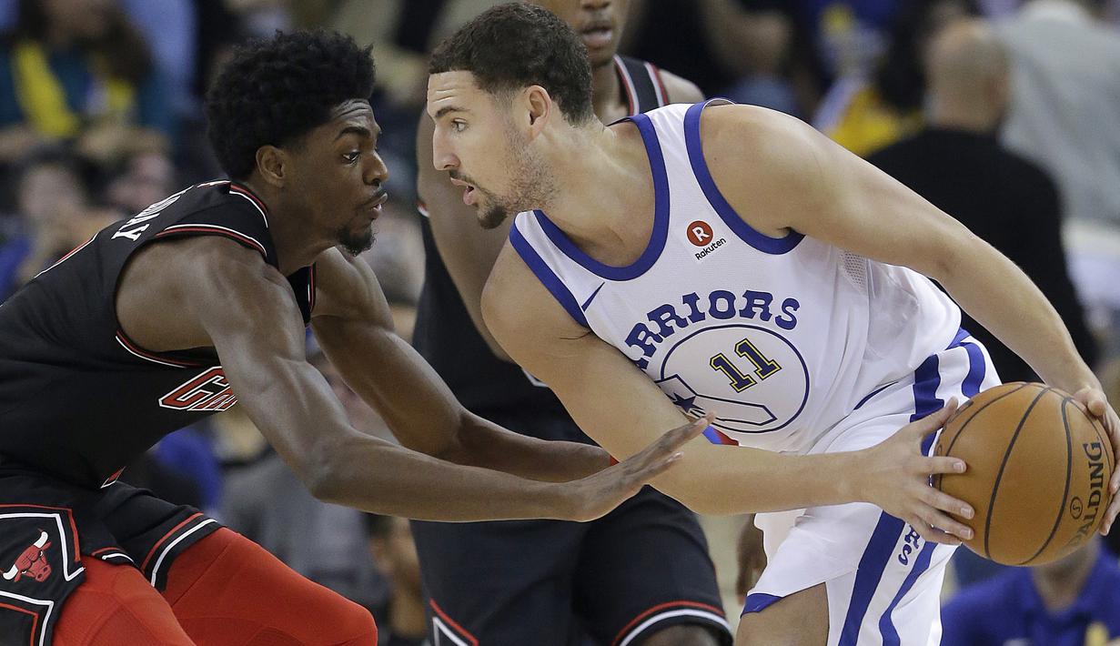 Pemain Warriors, Klay Thompson (kanan) mencoba melewati adangan pemain Chicago Bulls, Justin Holiday pada laga NBA basketball game di Oracle Arena, Oakland, (24/11/2017). Warriors menang 143-94. (AP/Jeff Chiu)