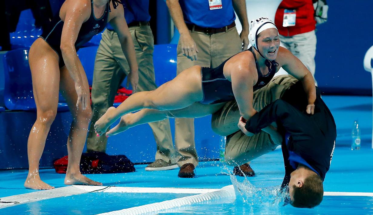 Anggota tim polo air putri AS mendorong pelatihnya, Adam Krikorian, ke kolam setelah meraih emas dengan mengalahkan Belanda di Kejuaraan Dunia Akuatik 2015 di Kazan, Rusia. (7/8/2015). (Reuters/Michael Dalder)