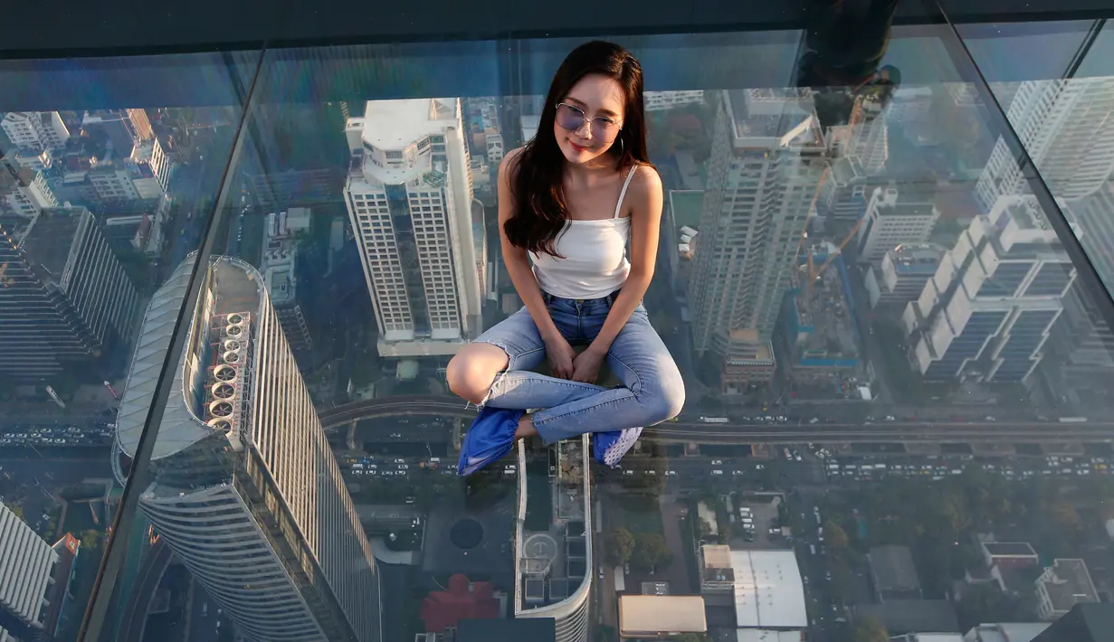Wisatawan duduk di dek kaca gedung King Power Mahanakhon, Bangkok, Thailand, Rabu (21/11). Dari Gedung King Power Mahanakhon menawarkan pemandangan Kota Bangkok secara 360 derajat. (AP Photo/Sakchai Lalit)