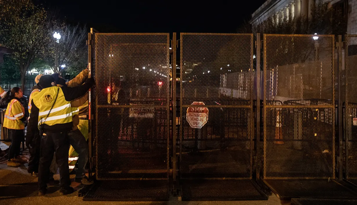 Pekerja memasang pagar besi di pintu masuk Gedung Putih mengantisipasi kerusuhan menjelang Pilpres Amerika Serikat di Washington DC, Senin (2/11/2020). Sebagai persiapan kemungkinan ada aksi terorisme atau protes massa, Gedung Putih membangun pagar baru. (Chris McGrath/Getty Images/AFP)