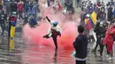 Seorang pengunjuk rasa antipemerintah mengembalikan tabung gas air mata ke polisi saat bentrokan di Bogota, Kolombia, Rabu (5/5//2021). Protes menentang proposal reformasi pajak terus berlanjut meski Presiden Ivan Duque telah mencabutnya. (AP Photo/Fernando Vergara)
