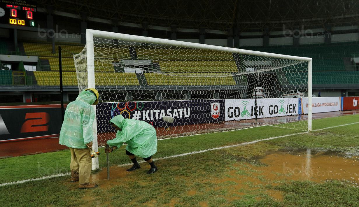 Petugas membuat lubang resapan untuk menguras air yang menggenangi lapangan di Stadion Patriot, Bekasi, Senin (13/11/2017). Drainase yang buruk menyebabkan lapangan terendam air. (Bola.com/M Iqbal Ichsan)
