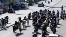 Para pengendara sepeda motor ikut mengikuti dari belakang saat para ppeserta memacu tunggangannya dalam perlombaan balap gerobak sapi di Kolombo, Sri Lanka, Sabtu (20/4). (LAKRUWAN WANNIARACHCHI/AFP)