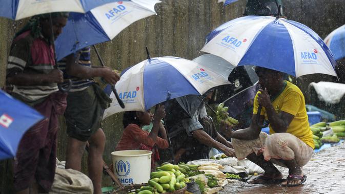 Seorang anak pengungsi Rohingyah menjual timun selama musim hujan di kamp pengungsi Kutupalong di Ukhia (12/9/2019). Kamp pengungsi Kutupalong dan Nayapara memiliki populasi sekitar 34.000 pengungsi yang terdaftar pada Juli 2017. (AFP Photo/Munir Uz Zaman)