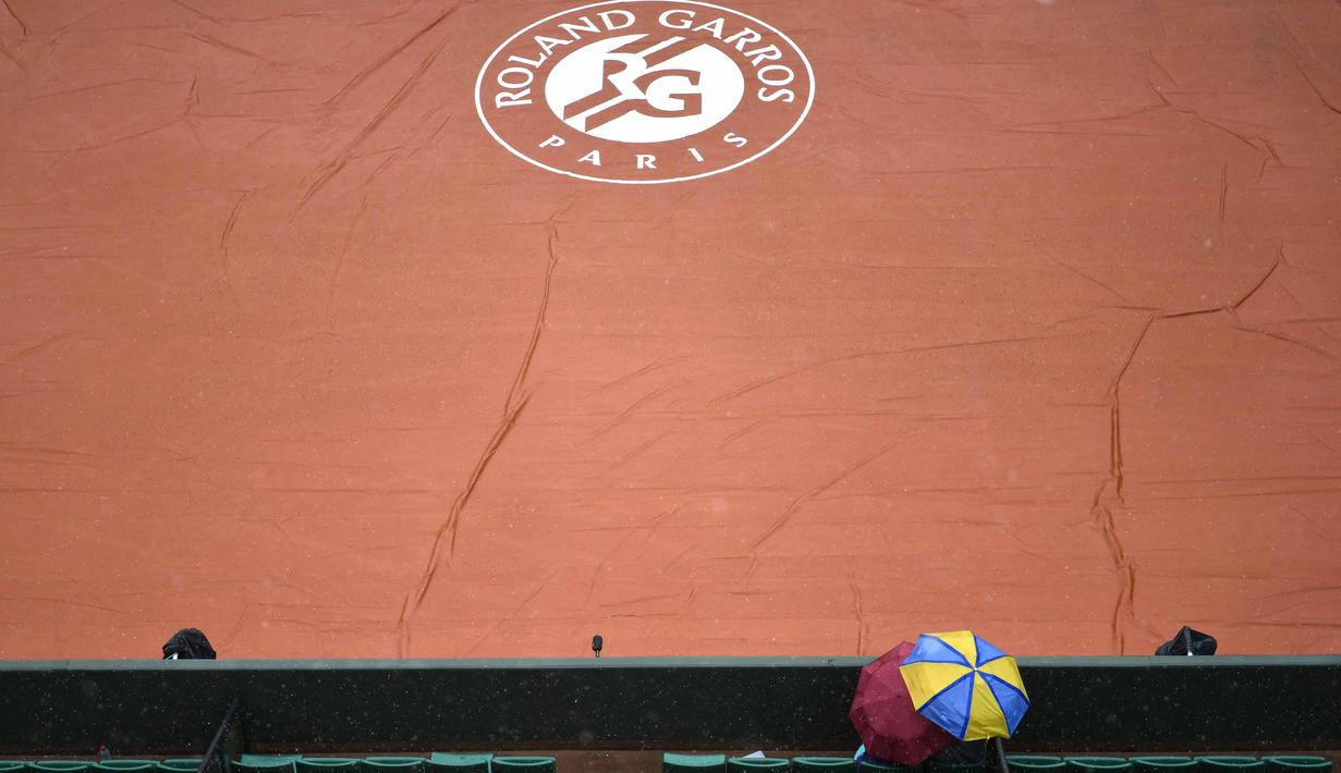 Penonton menggunakan payung menyaksikan lapangan Roland Garros yang ditutup tarpal saat hujan pada turnamen Prancis Terbuka 2016 di Roland Garros, (28/5/2016). (AFP/Philippe Lopez)