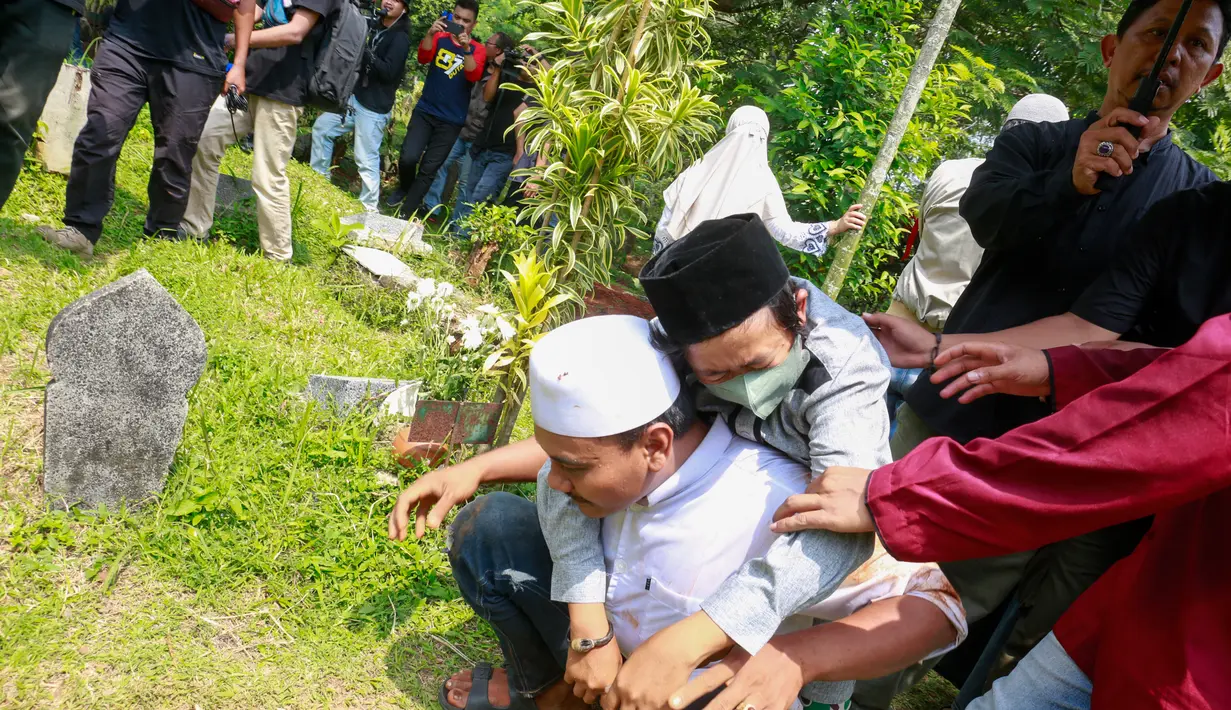 Setelah pemakaman selesai, Adul tak langsung pulang melainkan mendoakan sang ibunda. Duka mendalam hingga membuat Adul tampak lemas hingga digendong oleh salah satu kerabatnya. [Foto: Muhammad Akrom Sukarya/© KapanLagi.com]