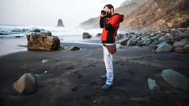 Seorang laki-laki sedang memotret di tepi pantai (Foto Dok: Freepik/wirestock)