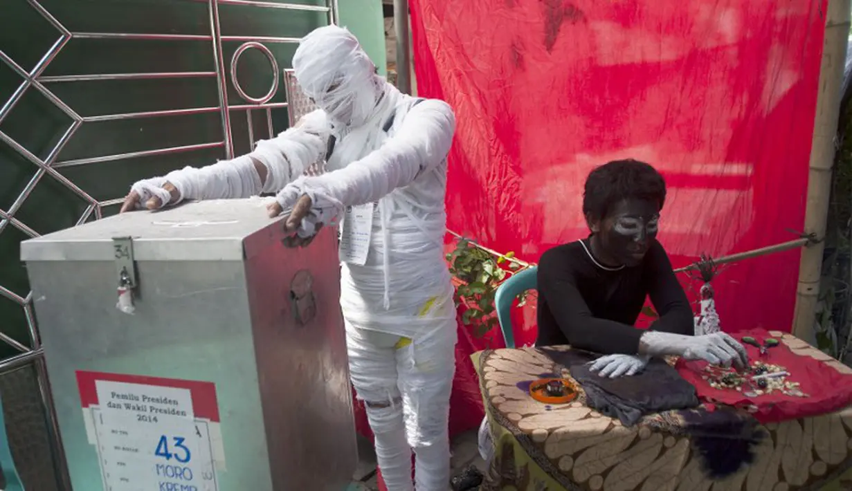 Untuk menarik minat para pemilih untuk mencoblos ditempatnya petugas TPS ini rela menyulap dirinya menjadi hantu, Surabaya, Rabu (9/7/2014) (AFP PHOTO/JUNI KRISWANTO)