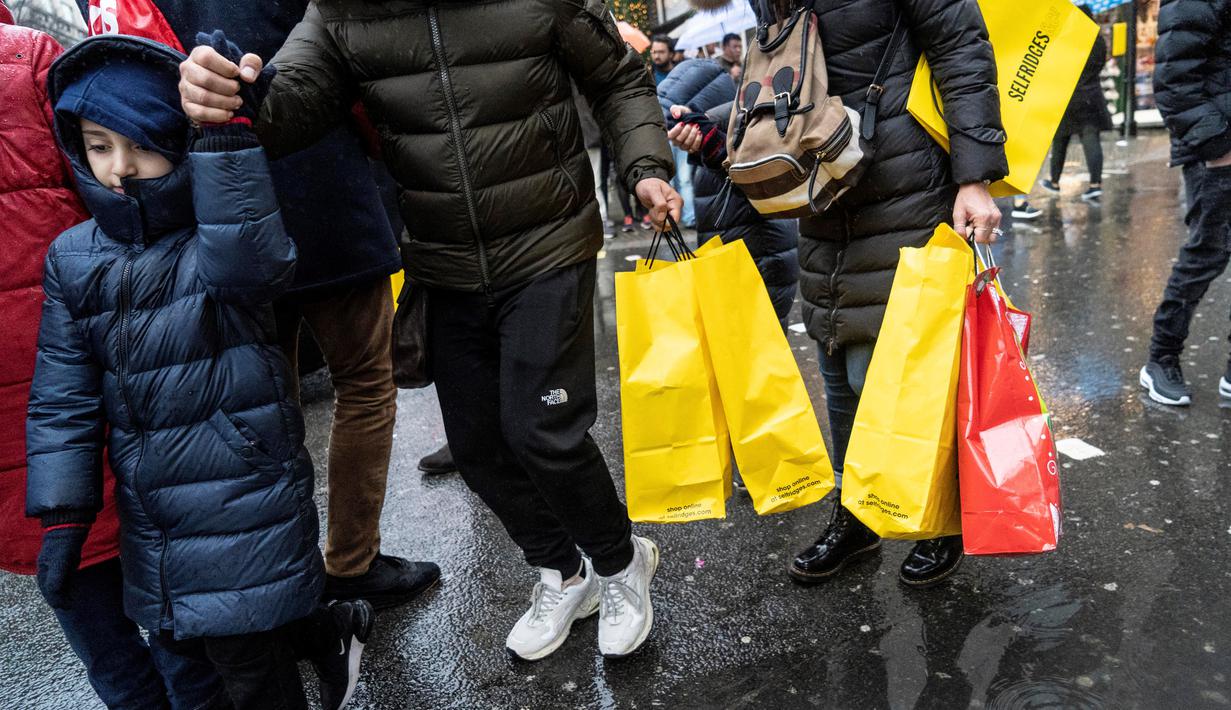 Pemburu diskon membawa kantong belanja mereka selama Boxing Day di pusat kota London, Kamis (26/12/2019). Boxing Day merupakan tradisi hari belanja terbesar tahunan yang diperingati setiap 26 Desember atau sehari setelah Natal dan menjadi hari libur nasional di Inggris. (Niklas HALLE'N/AFP)