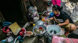 Warga membersihkan perabotan usai terendam banjir di permukiman kawasan Kampung Melayu, Jakarta, Selasa (9/2/2021). Banjir yang berangsur surut dimanfaatkan warga untuk membersihkan rumah dan barang-barang dari endapan lumpur. (Liputan6.com/Faizal Fanani)