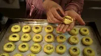 Perempuan Palestina membuat kue tradisional berisi kurma dan kacang-kacangan dalam persiapan untuk liburan Idul Fitri, di kota Hebron, Tepi Barat, pada 28 April 2022. Orang-orang di Palestina mempunyai tradisi lebaran yang unik dan khas yaitu dengan membuat kue kering dengan aneka bentuk dan rasa. (HAZEM BADER / AFP)