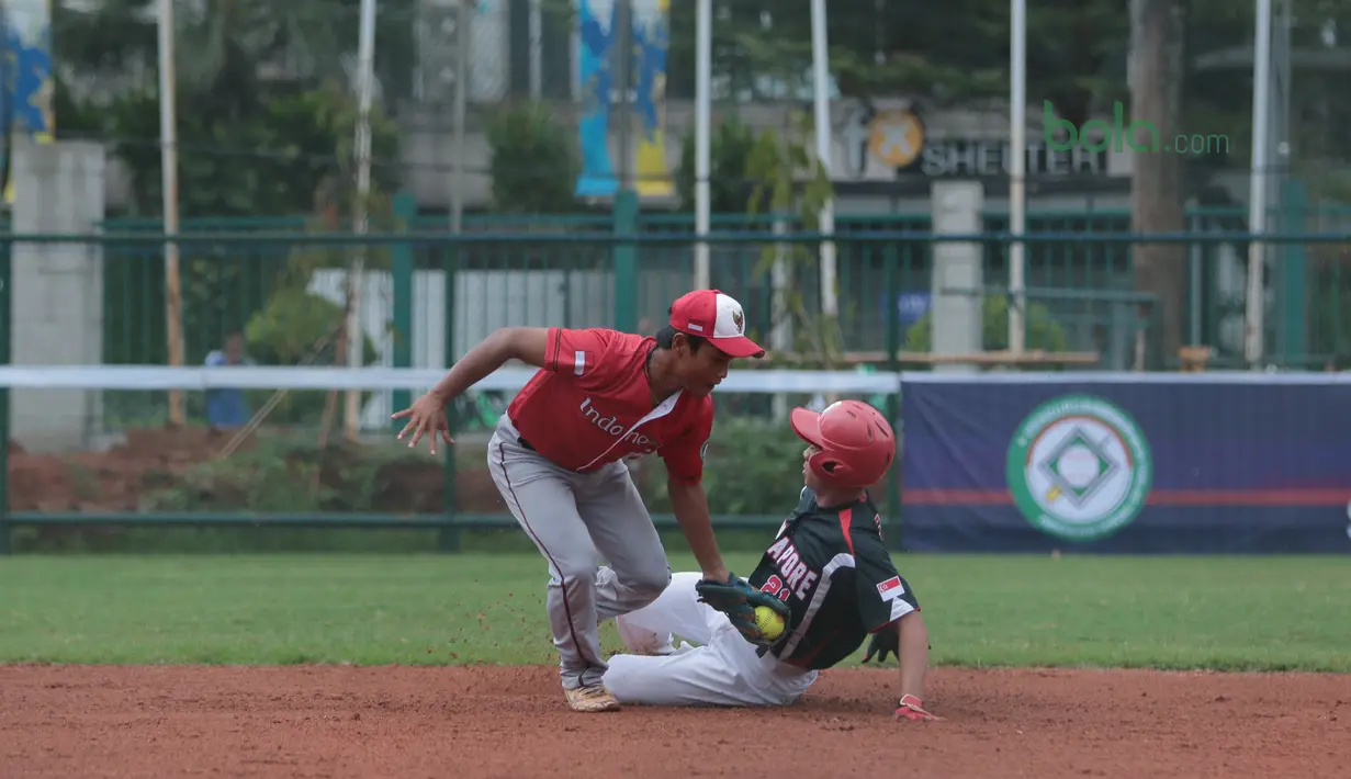 Pemain Indonesia, Hermansyah (kiri) mencoba mematikan langkah pemain Singapura pada laga Asian Softball Championship di Senayan, Jakarta,Selasa (25/4/2018). Indonesia menang atas Singapura 8-2. (Bola.com/Nick Hanoatubun)