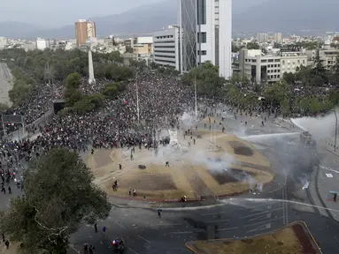 Polisi dan demonstran bentrok dalam protes anti-pemerintah di Santiago, Chile (4/10/2019). Ribuan warga Chile kembali turun ke jalan memprotes layanan sosial yang lebih baik. (AP Photo/Esteban Felix)
