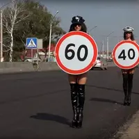 Dua perempuan terlihat bertelanjang dada sambil memegang batas laju kecepatan di dekat area penyeberangan, Rusia. (Daily Mail)