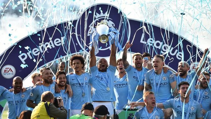 Kapten Manchester City, Vincent Kompany, mengangkat piala saat merayakan gelar juara Liga Inggris di Stadion American Express Community, Brighton, Minggu (12/5). City juara setelah unggul satu poin dari Liverpool. (AFP/Glyn Kirk)