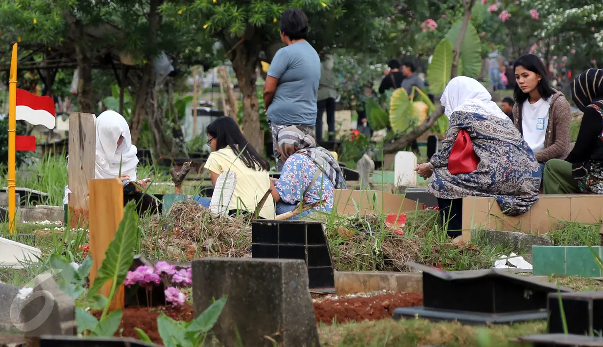 Warga memanjatkan doa di samping pusara keluarga saat berziarah di TPU Karet Bivak, Jakarta, Minggu (14/6). Menjelang Ramadan, umat muslim melakukan ziarah kubur untuk mendoakan keluarga dan kerabatnya yang telah wafat. (Liputan6.com/Helmi Afandi)