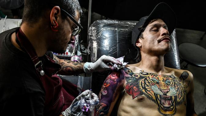 Seniman membuat tato di tangan seorang pria saat acara Expotattoo Colombia 2019 di Medellin, departemen Antioquia (2/6/2019). Para penggila tato antusias untuk mentato tubuhnya di festival tato terbesar di negara tersebut. (AFP Photo/Joaquim Sarmiento)