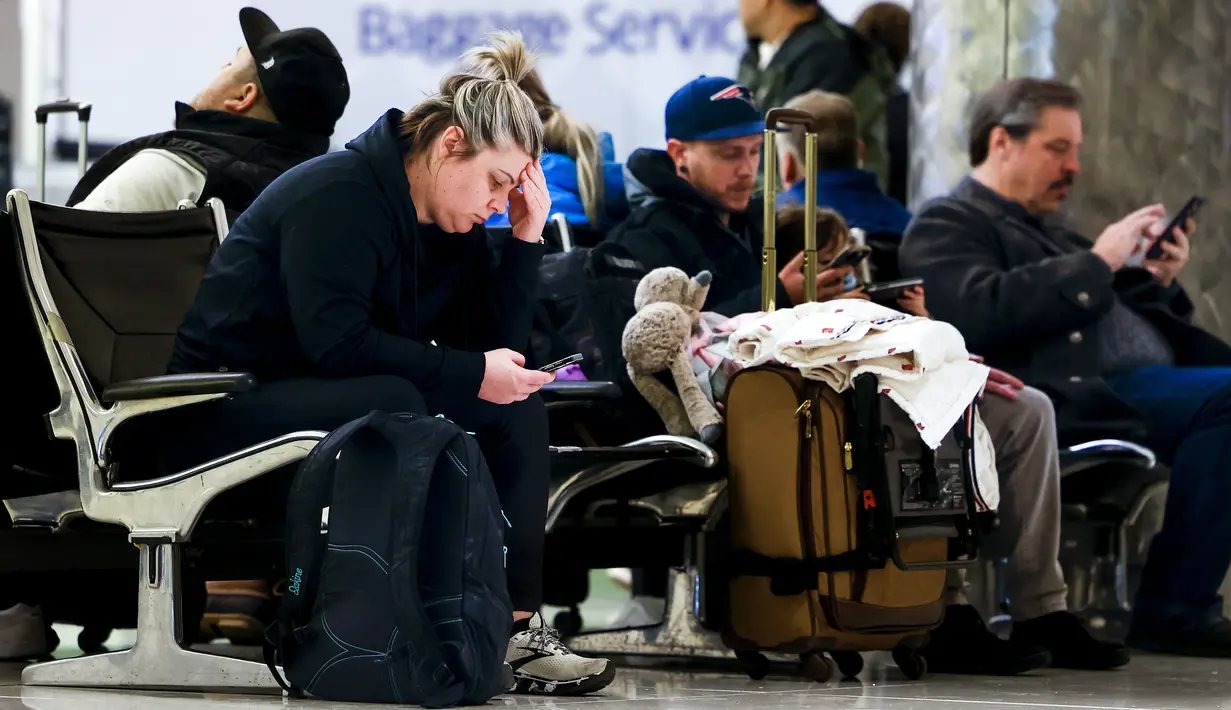 Mairi Risner duduk di Bandara Internasional Denver setelah penerbangannya dibatalkan karena badai musim dingin di Denver, Colorado, Rabu (22/2/2023). Selain mambatalkan penerbangan, badai musim dingin yang besar menghantam Northern Plains dan Upper Midwest dengan angin kencang dan salju lebat pada hari Rabu yang memaksa ratusan sekolah tutup. (Michael Ciaglo/Getty Images/AFP)