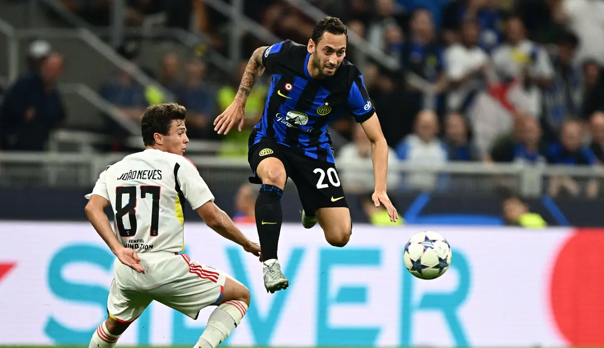 Gelandang Benfica #87 Joao Neves berebut bola dengan gelandang Inter Milan #20 Hakan Calhanoglu pada matchday 2 Liga Champions 2023/2024 di Giuseppe Meazza, Italia, Rabu (4/102/2023) WIB. (GABRIEL BOUYS / AFP)