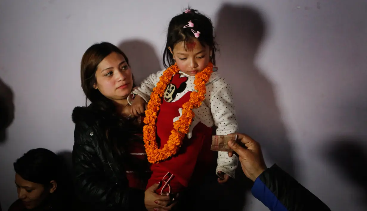 Nihira Bajracharya digendong ibunya saat dibawa untuk menjadi Dewi Hidup atau Kumari di kuil Hindu Patan, Lalitpur, Nepal (5/2). Nihira Bajracharya akan menjadi Kumari setelah pendahulunya pensiun karena mencapai pubertas. (AP Photo / Niranjan Shrestha)
