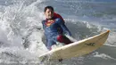 Peserta berselancar dengan mengenakan pakaian Superman selama ikuti lomba selancar di Santa Monica, Amerika Serikat, Sabtu (31/10/2015). Perlombaan ini mewajibkan peserta mengenakan kostum bertema Halloween. (REUTERS/Lucy Nicholson)