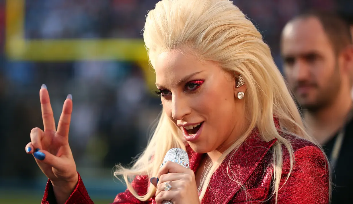Penyanyi Lady Gaga saat menyanyikan lagu kebangsaan AS pada pembukaan Super Bowl 50 di Santa Clara, California, Minggu (7/2). Pelantun lagu Judas itu mengaplikasikan eyeshadow merah glitter senada dengan busananya. (Christopher Polk/Getty Images/AFP)