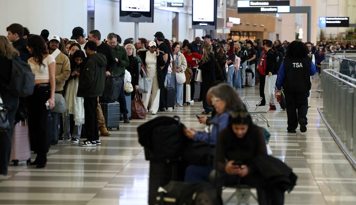 Para penumpang mengantre untuk melewati pemeriksaan keamanan di bandara LaGuardia New York pada Minggu 22 Maret 2026. Pemerintahan Presiden Donald Trump akan mengambil langkah drastis untuk mengatasi kekacauan di sejumlah bandara Amerika Serikat. (CHARLY TRIBALLEAU/AFP)