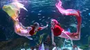 Dengan mengenakan kostum putri duyung, para penyelam berenang bersama ikan-ikan yang ada dalam akuarium. Ada ikan pari hingga dan ikan-ikan yang lebih kecil. (AP Photo/Lee Jin-man)