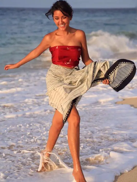 Bermain air di pantai, kali ini Titi hanya mengenakan kain berwarna hitam putih dan bercorak garis-garis. Untuk atasannya, ia hanya memakai kemben berwarna merah. Sangat eksotis ya perempuan yang satu ini? (Instagram/titirajobintang)