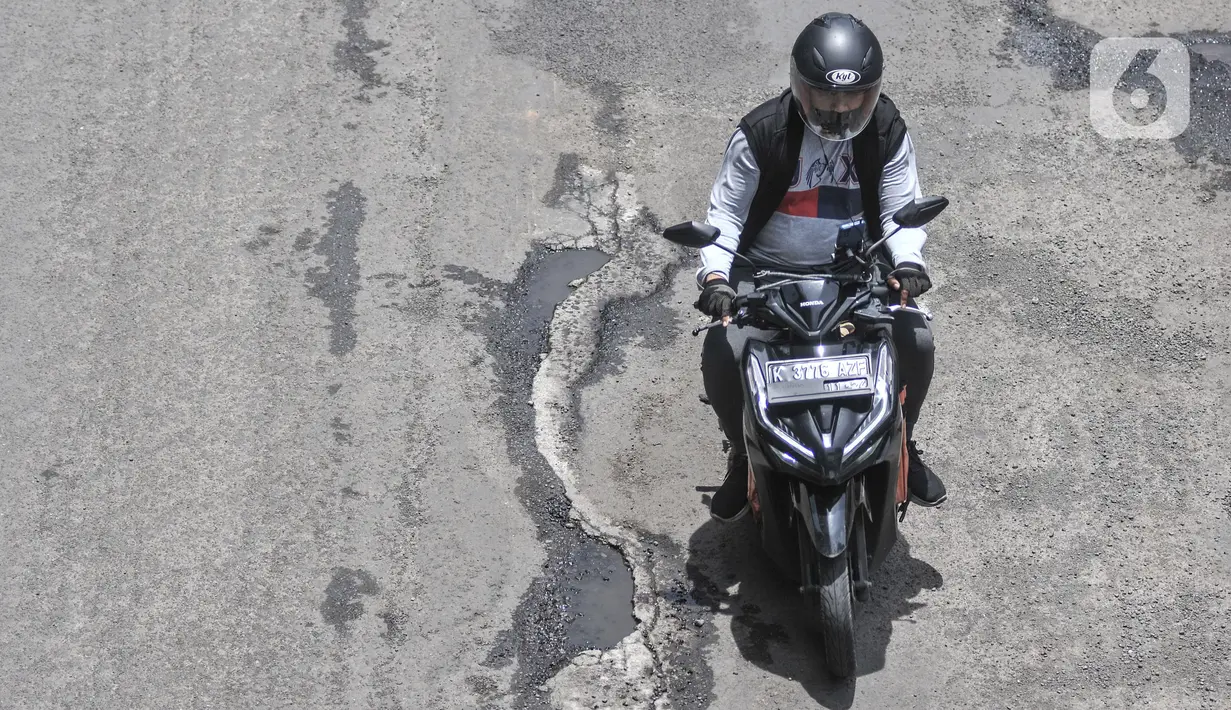 Pengendara motor menghindari jalan rusak dan berlubang saat melintas di Jalan HR Rasuna Said, Kuningan, Jakarta Selatan, Senin (24/10/2022). Minimnya pengawasan dan perawatan dari pihak terkait menyebabkan jalan rusak dan berlubang imbas proyek pembangunan stasiun LRT Jabodebek tersebut sudah terjadi sejak dua bulan lalu yang dapat menimbulkan kecelakaan serta mengancam keselamatan pengendara. (merdeka.com/Iqbal S. Nugroho)