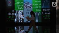 Pekerja melintas di depan layar Indeks Harga Saham Gabungan (IHSG) di BEI, Jakarta, Senin (3/1/2022). Pada pembukan perdagagangan bursa saham 2022 Indeks Harga Saham Gabungan (IHSG) langsung menguat 7,0 poin atau 0,11% di level Rp6.588,57. (Liputan6.com/Angga Yuniar)
