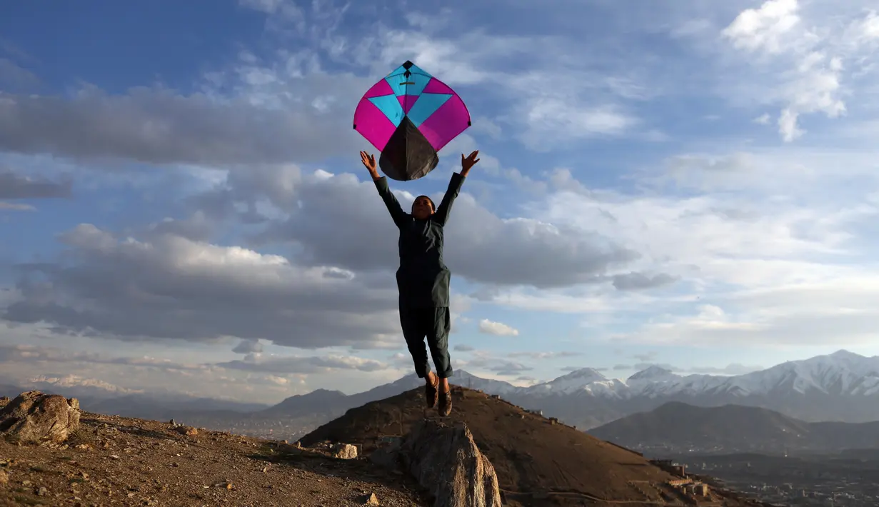 Seorang anak laki-laki Afghanistan melepaskan layang-layang saat bermain di puncak bukit di pinggiran Kabul, Afghanistan (4/3). (AP Photo/Rahmat Gul)