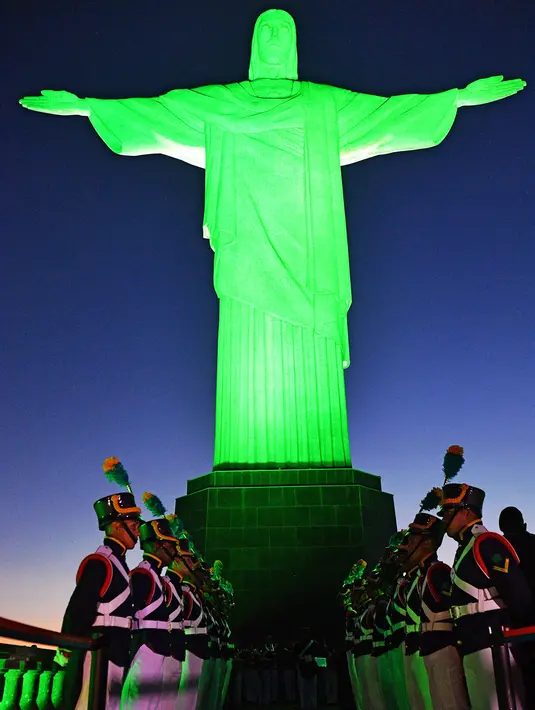 Tentara dalam upacara adat berbaris di depan patung Kristus Penebus setelah dinyalakan hijau untuk menandai hari Tentara Nasional, di Rio de Janeiro, Brasil (19/4). (AFP Photo/Carl De Souza)
