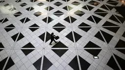 Seorang pria yang mengenakan masker untuk membantu mengekang penyebaran virus corona berjalan di sebuah gedung di Tokyo, Kamis, (27/8/2020). (AP Photo/Eugene Hoshiko)