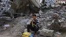 Untuk mencapai Pasar Al-Zawiya, warga harus berjalan melewati reruntuhan bangunan akibat konflik antara Israel dan Hamas. Tampak dalam foto, seorang pemuda Palestina duduk di reruntuhan di pasar Zawiya, Kota Gaza, pada Rabu 18 Februari 2026. (Omar AL-QATTAA/AFP)
